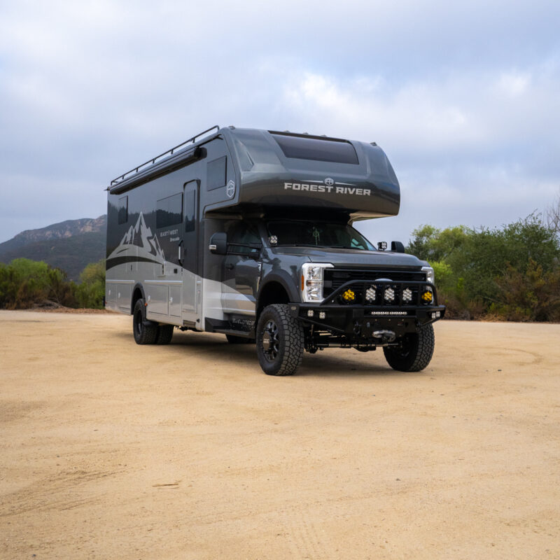 WeldTec Designs Sentinel front bumper installed on a Ford F-550/F-600 Forest River Super C RV with off-road tires, auxiliary LED lighting, and integrated winch.
