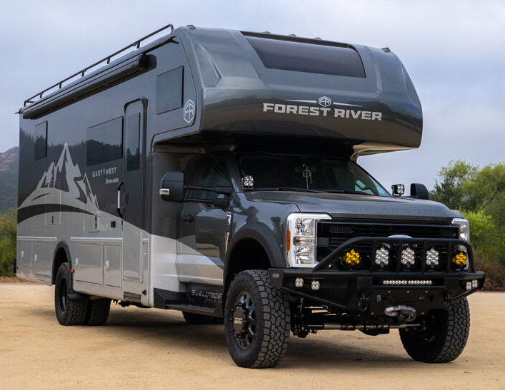WeldTec Designs Sentinel front bumper installed on a Ford F-550/F-600 Forest River Super C RV with off-road tires, auxiliary LED lighting, and integrated winch.