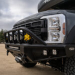 WeldTec Designs Sentinel front bumper installed on a Ford F-550/F-600 Forest River Super C RV with off-road tires, auxiliary LED lighting, and integrated winch.