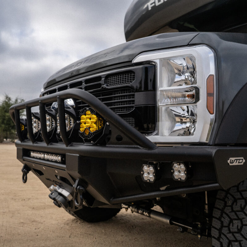 WeldTec Designs Sentinel front bumper installed on a Ford F-550/F-600 Forest River Super C RV with off-road tires, auxiliary LED lighting, and integrated winch.